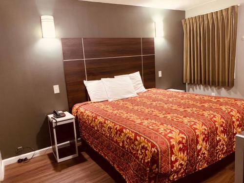 a hotel room with a bed with a wooden headboard at Red Carpet Inn - Norristown in Norristown