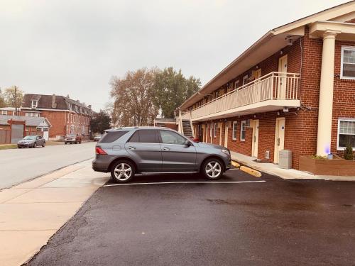 a gray car parked in a parking lot next to a building at Red Carpet Inn - Norristown in Norristown