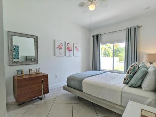 1 dormitorio con cama, espejo y ventana en Coral Reef Villa, en Fort Lauderdale