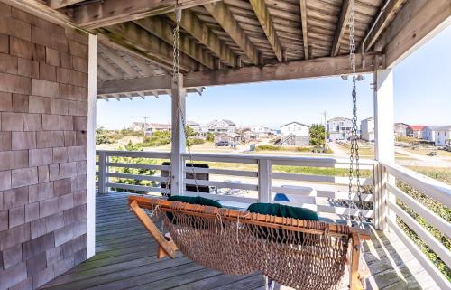 a porch swing with green cushions on a house at Sea Shellter in Whalebone