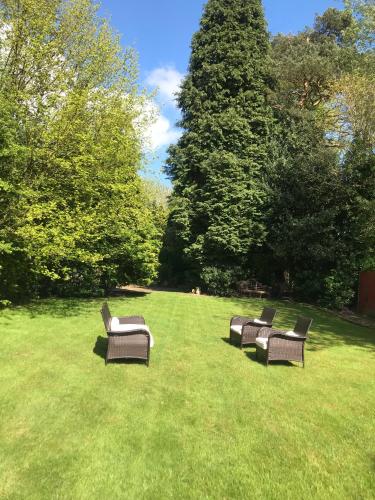 a group of chairs sitting in the grass at Beautiful mansion in private gated Rd Hot tub FREE SAUNA in Luton