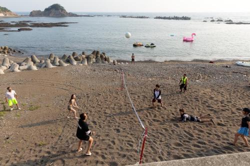 a group of people on a beach playing with a kite at MARINE-Q in Inami