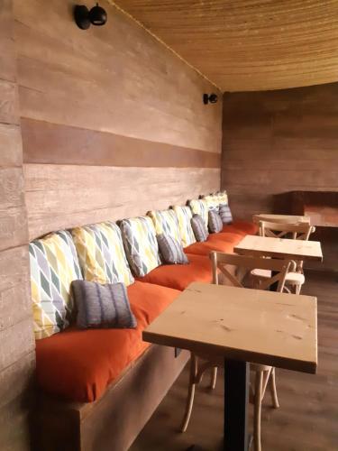 a room with a long couch with pillows and tables at La Quinta Glamping - Lago de Tota in Cuítiva
