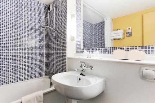 ein weißes Badezimmer mit einem Waschbecken, einer Badewanne und einem Waschbecken in der Unterkunft Kyriad Angers Sud Ponts-De-Cé in Les Ponts-de-Cé