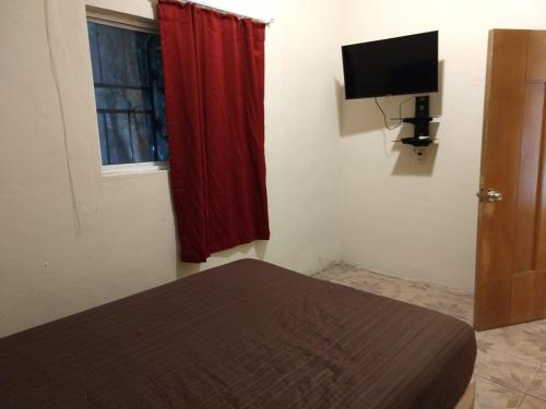 - une chambre avec un lit doté d'un rideau rouge et d'une télévision dans l'établissement Departamento a 5 minutos de playa Mismaloya, Puerto Vallarta, à Puerto Vallarta