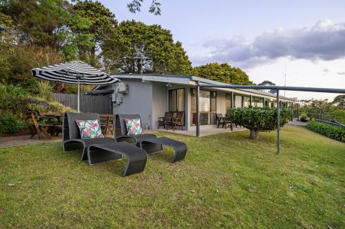 a house with chairs and an umbrella in a yard at The Bird House in Mount Tamborine