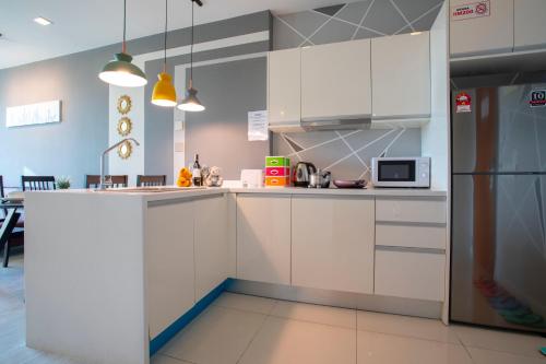 a kitchen with white cabinets and a refrigerator at Cozy Living Sky Apartment in Kota Kinabalu