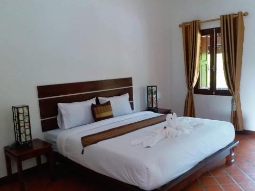 a bedroom with a large bed with white sheets at Villa Chitchareune 2 in Luang Prabang