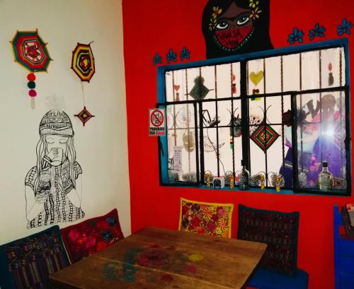a dining room with a table and a red wall at Casa Apapacho hostel in San Cristóbal de Las Casas