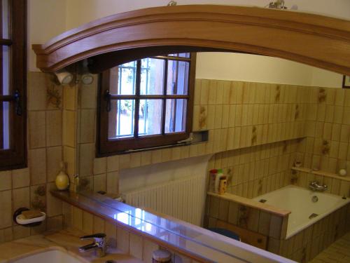 y baño con lavabo, espejo y bañera. en Maison provençale chaleureuse avec piscine en Mouriès