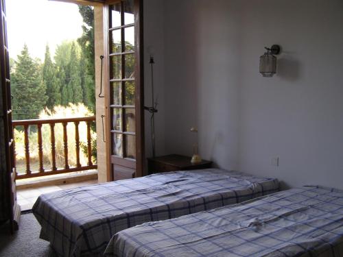 1 dormitorio con 2 camas y puerta a un balcón en Maison provençale chaleureuse avec piscine en Mouriès