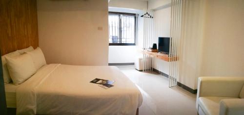 a hotel room with a bed and a chair at Loyy Hotel in Chiang Mai