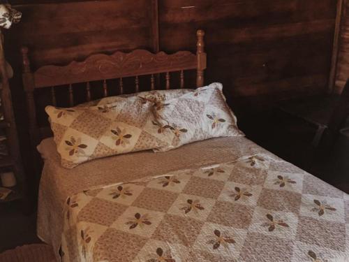 a bed with a quilt and pillows on it at Cabana Alecrim do Campo in Itatiaia