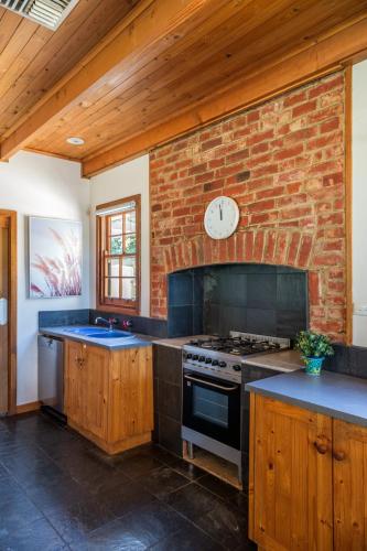 a kitchen with a brick wall and a clock on the wall at McLaren Vale Getaways in McLaren Flat