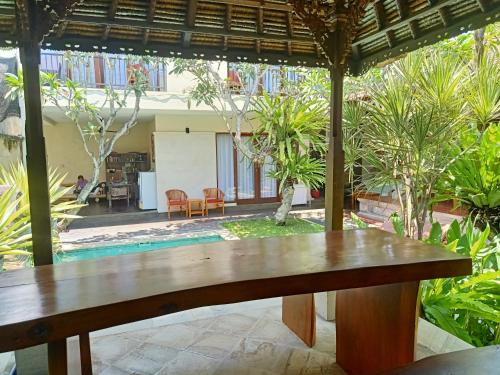 a wooden table under an umbrella in a courtyard at Ngetis Home Stay in Sanur