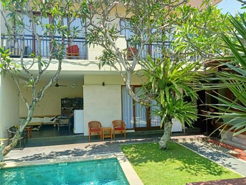 a house with a swimming pool in a yard with trees at Ngetis Home Stay in Sanur