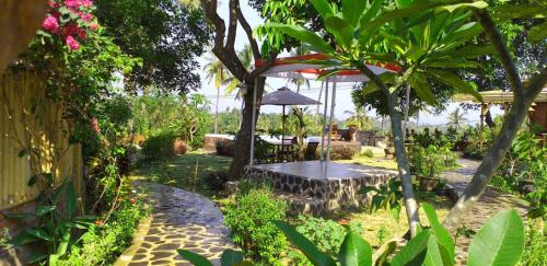 a table with an umbrella in a garden at Lafyu Bali in Singaraja