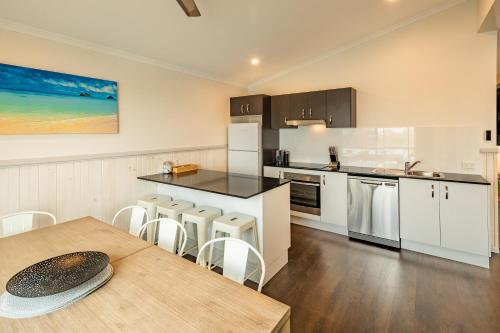 a kitchen with white cabinets and a table and chairs at Ingenia Holidays White Albatross in Nambucca Heads