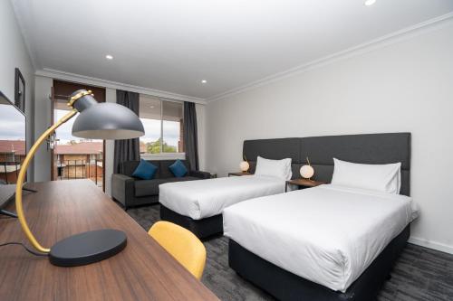 a hotel room with two beds and a desk at Littomore Suites Bathurst in Bathurst