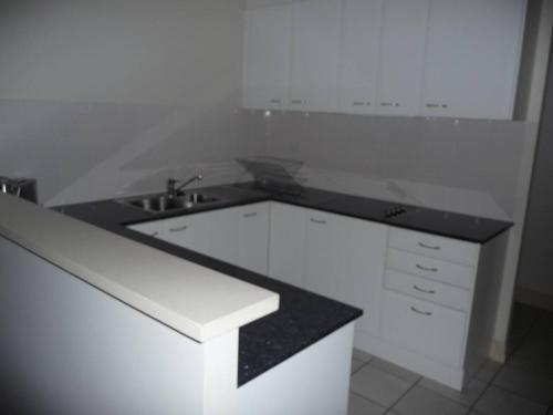 a white kitchen with a sink and a counter at City Getaway 3 Bedroom Adelaide's East End in Adelaide