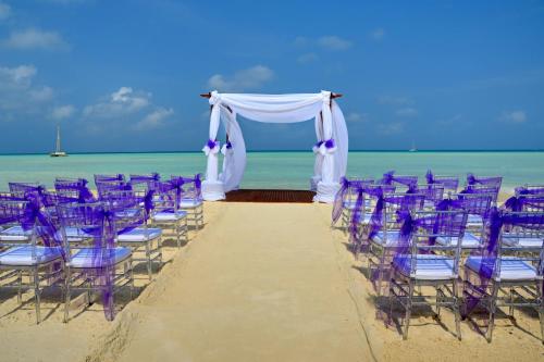 a wedding ceremony on the beach with purple chairs at Barceló Aruba - All Inclusive in Palm-Eagle Beach