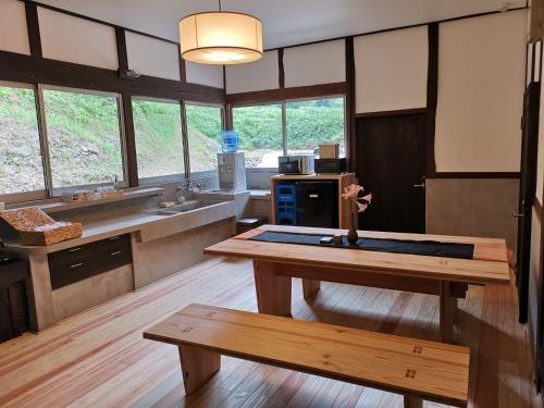 a large kitchen with a wooden table and a bench at せとうち古民家ステイズHiroshima 不老仙 in Shōbara