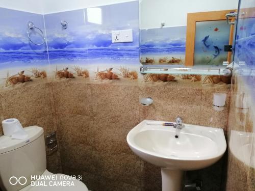 a bathroom with a sink and a toilet at Kasun Hotel in Koslanda