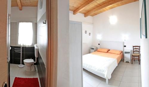 een witte slaapkamer met een bed en een badkamer bij B&B S'Ena in Suni