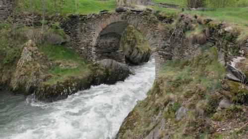 a stone bridge over a river with rushing water at Pensio La Creu in Esterri d'Àneu