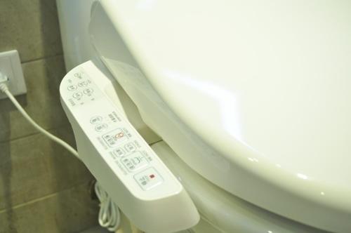a remote control next to a toilet in a bathroom at Green Hotel - West District in Taichung