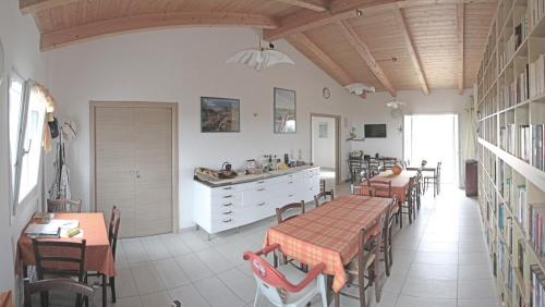 a dining room with tables and chairs and a kitchen at B&B S'Ena in Suni
