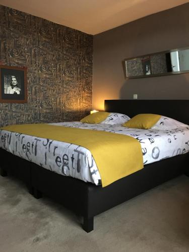 a bedroom with a large bed with white sheets and yellow pillows at B&B Le Grand Cabaret in Nieuwpoort
