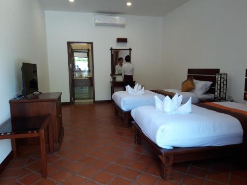 a hotel room with three beds and a mirror at Villa Chitchareune 2 in Luang Prabang