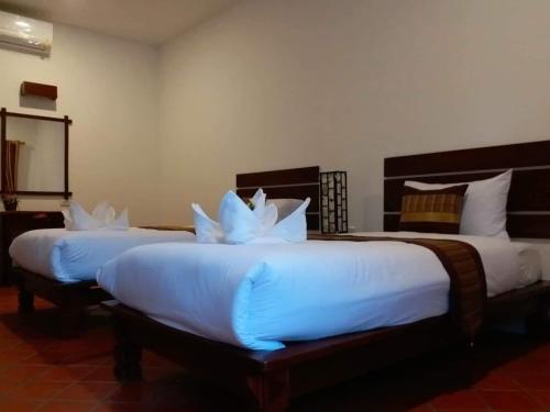 two beds in a hotel room with white pillows at Villa Chitchareune 2 in Luang Prabang