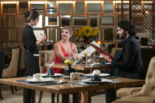 a group of people standing around a table in a restaurant at The Oriental Jade Hotel in Hanoi