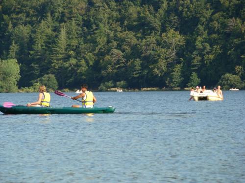 two children in kayaks on a lake with a boat at Logis Hôtel Le Beau Site in Chambon-sur-Lac