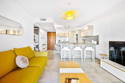 un salon avec un canapé jaune et une cuisine dans l'établissement Domaine du Frassu, T2 standing, plage à pied, à Porticcio