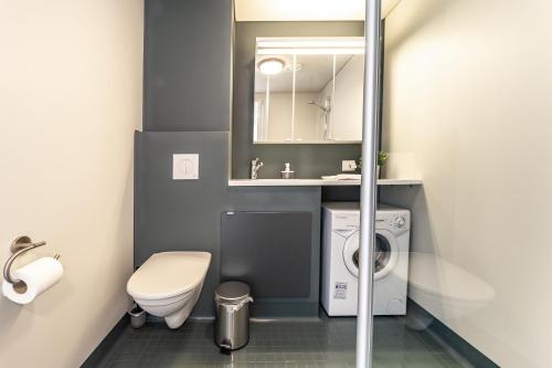 a bathroom with a toilet and a sink and a washing machine at Spot Apartments Rajakylä in Vantaa
