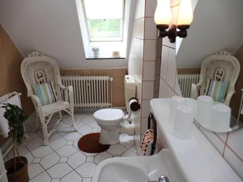 a bathroom with a toilet and a sink and two chairs at Der Alps Hof in Walsrode