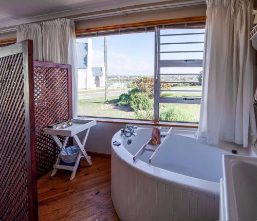 a bathroom with a large white tub and a window at Sitterus in Stilbaai