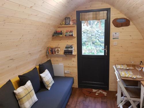 a living room with a blue couch and a door at Strathyre Camping Pods in Strathyre