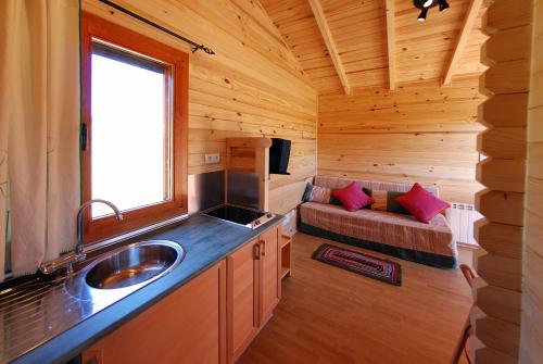 una cocina con fregadero en una cabaña de madera en Cabañas del Cortino, en Monleras
