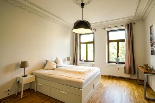 a white bedroom with a bed and two windows at ***Stylische Wohnung direkt am Hauptbahnhof*** in Leipzig