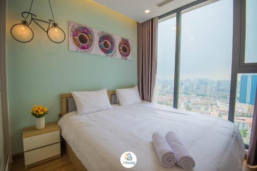 a bedroom with a white bed with a large window at Vinhomes Metropolis luxury Hotel & Residence in Hanoi