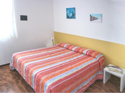 リニャーノ・サッビアドーロにあるCasa Marinaのベッドルーム1室(カラフルなストライプ毛布付きのベッド1台付)