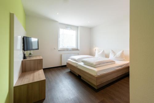 a bedroom with a bed and a flat screen tv at a2 HOTELS Denkendorf - Airport & Messe in Denkendorf