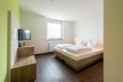 ein Schlafzimmer mit einem Bett und einem Flachbildfernseher in der Unterkunft a2 HOTELS Denkendorf - Airport & Messe in Denkendorf