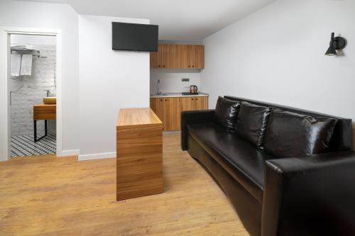 a living room with a black leather couch and a kitchen at Labirint Boutique Hotel in Bucharest