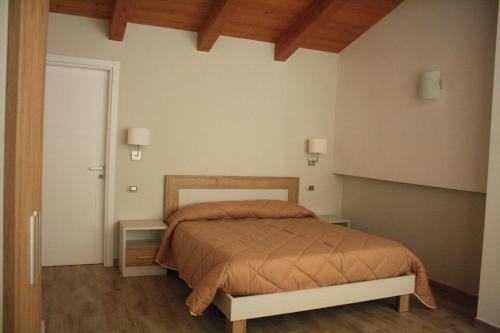 B&B Le Cinque Cime في فيدجانيلو: غرفة نوم مع سرير وطاولتين النهاية