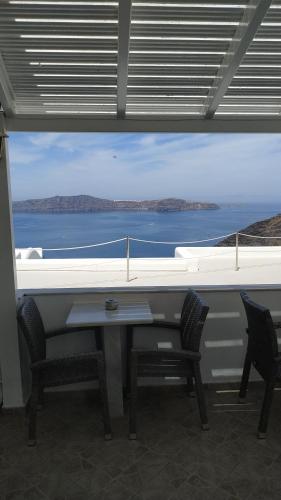 a table and chairs with a view of the ocean at Hotel Mylos in Firostefani